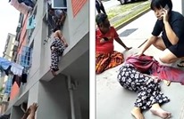 رجل يمسك امرأة من شعرها لمنع سقوطها من بناية (شاهد)